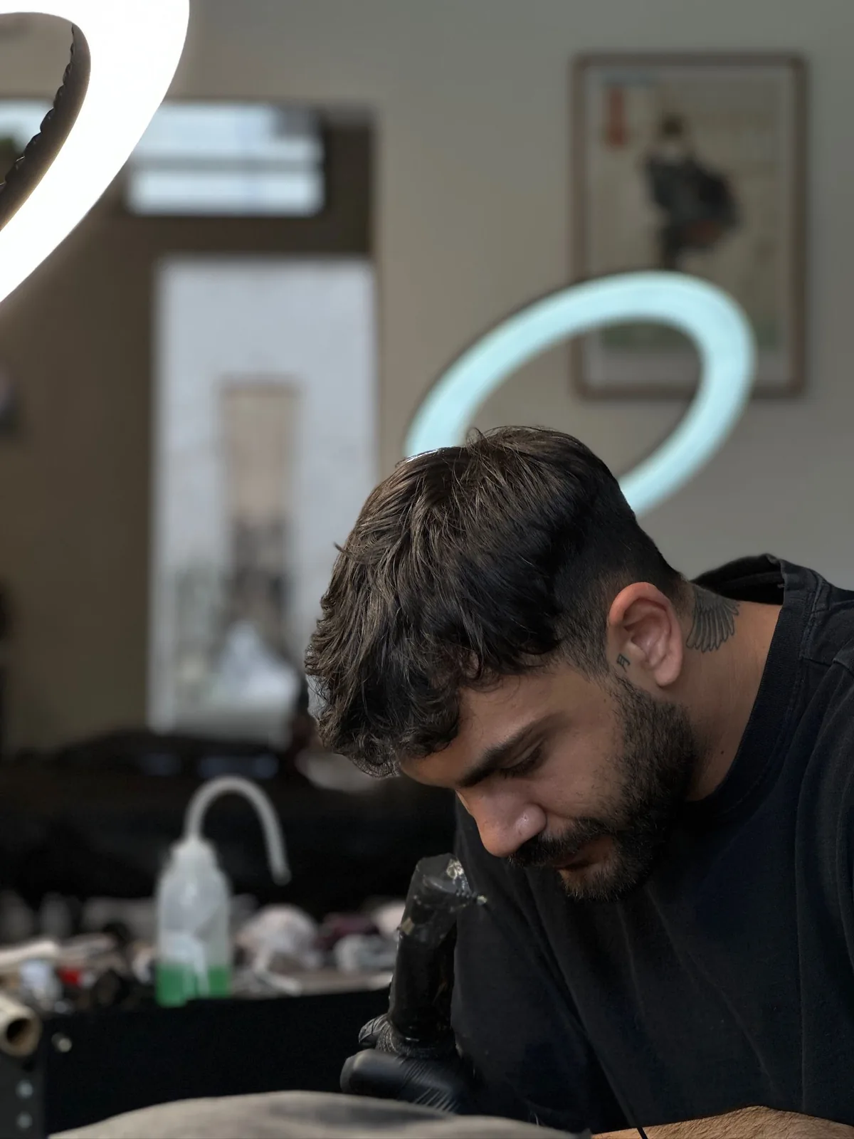 A 90 ink artist tattooing a client under a ring light